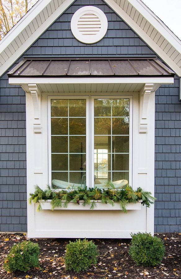 a window box with plants in it on the side of a blue house that has white trim and windows