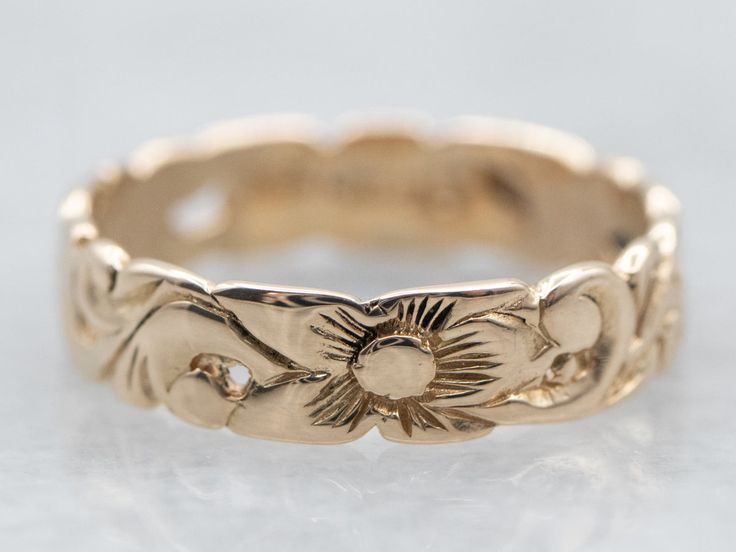 a gold ring with an intricate design on the outside and inside, sitting on a white surface