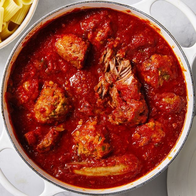 a pan filled with meatballs and sauce next to pasta