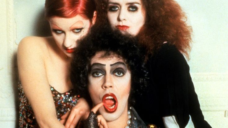 three women with makeup and hair are posing for the camera, one is sticking her tongue out