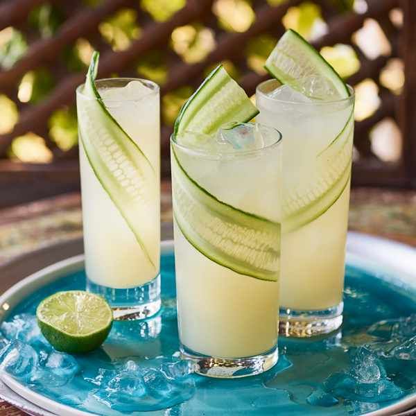 two glasses filled with cucumber and limeade sitting on top of a plate