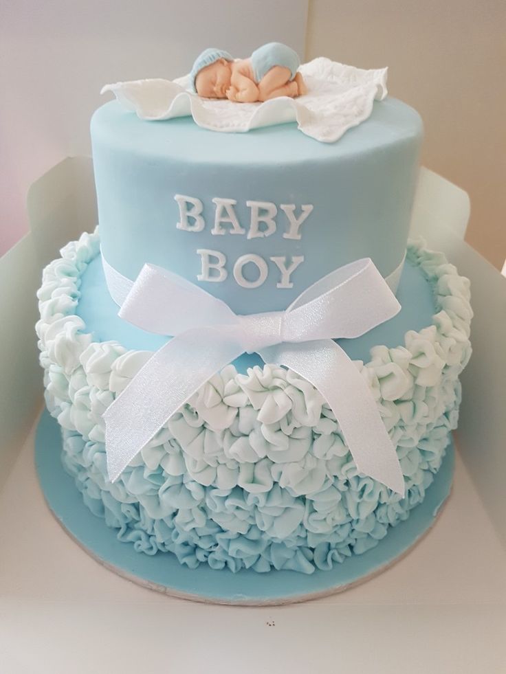 a blue and white cake with a baby boy on top