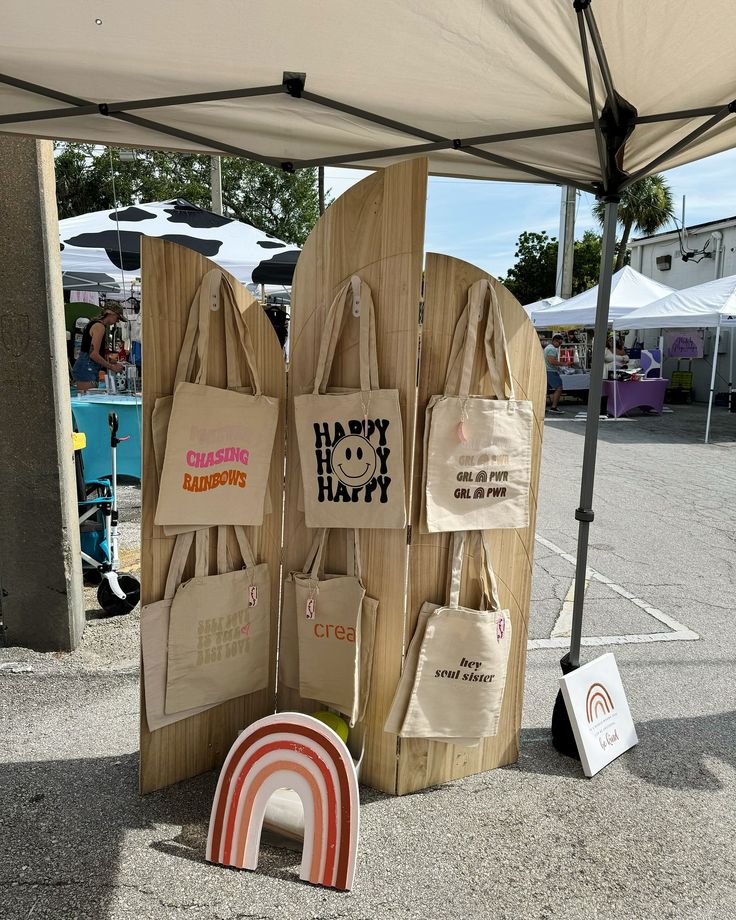 several bags on display under a tent at an outdoor market with the word happy hanz written on them