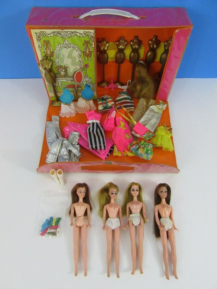 three barbie dolls are in a suitcase with clothes and other items on the table next to them