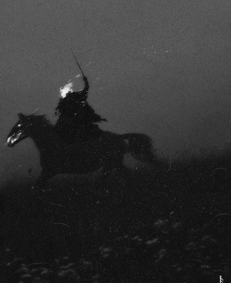 black and white photograph of a man on a horse in the dark with fog behind him