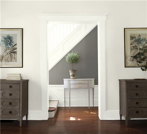 an empty room with blue walls and white trim on the door, two dressers and a potted plant