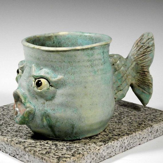 a ceramic fish cup sitting on top of a stone slab