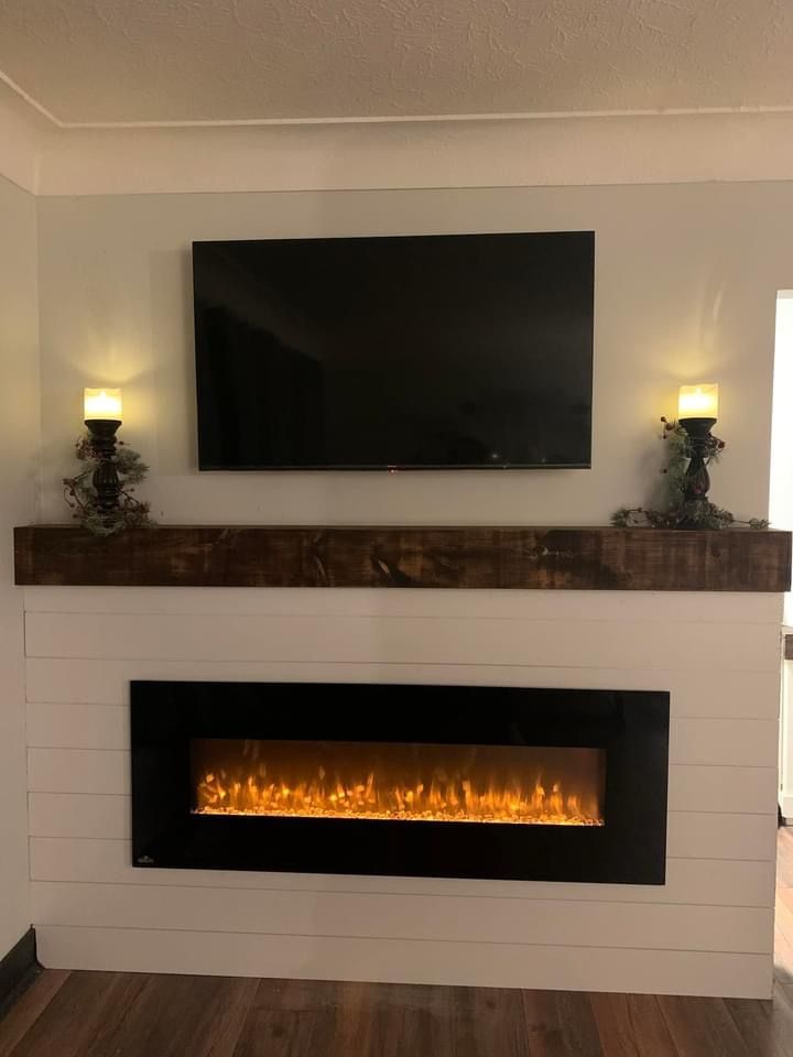 a white fireplace with a flat screen tv above it and two candles on either side