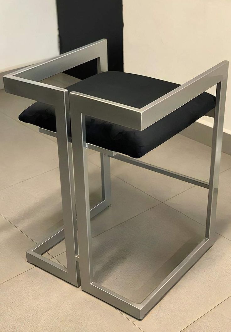 a black and silver chair sitting on top of a tile floor next to a wall