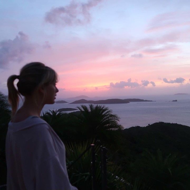 a woman looking out over the ocean at sunset