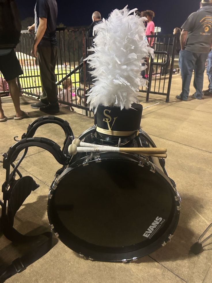 a drum kit with white feathers on it and people in the background looking at them