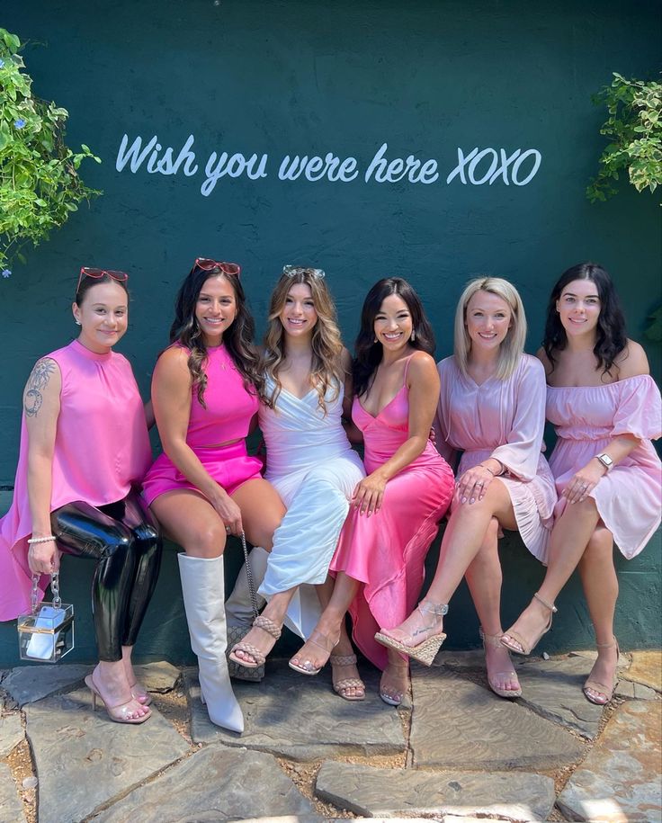 four women in dresses posing for a photo with the xoxo sign behind them