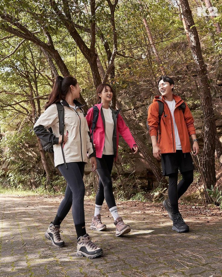 three people walking in the woods with backpacks on their back and one person wearing an orange jacket