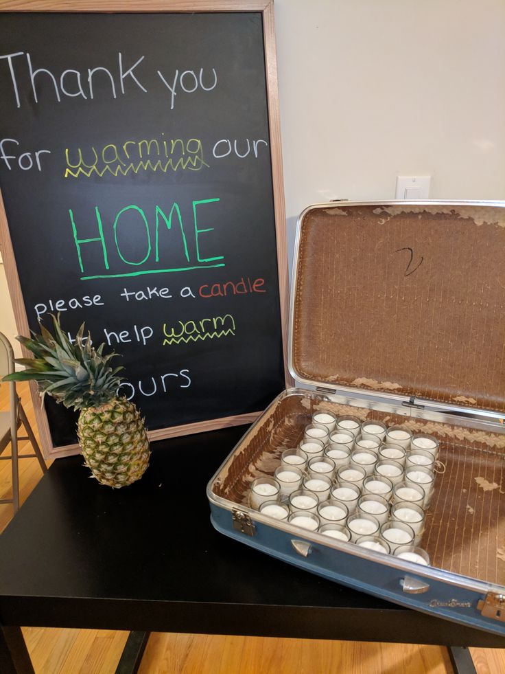 a pineapple sits next to a lunch box with tea lights in it and a chalkboard sign that says thank you for warming our home