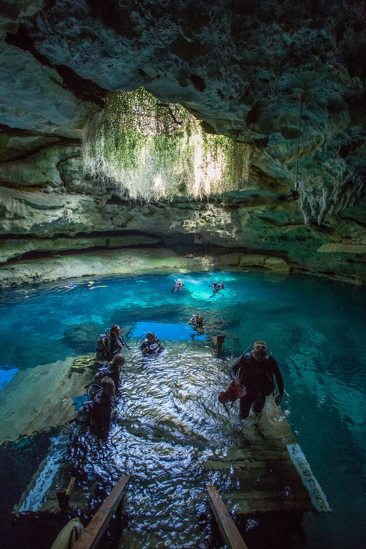 several people are swimming in the blue cave