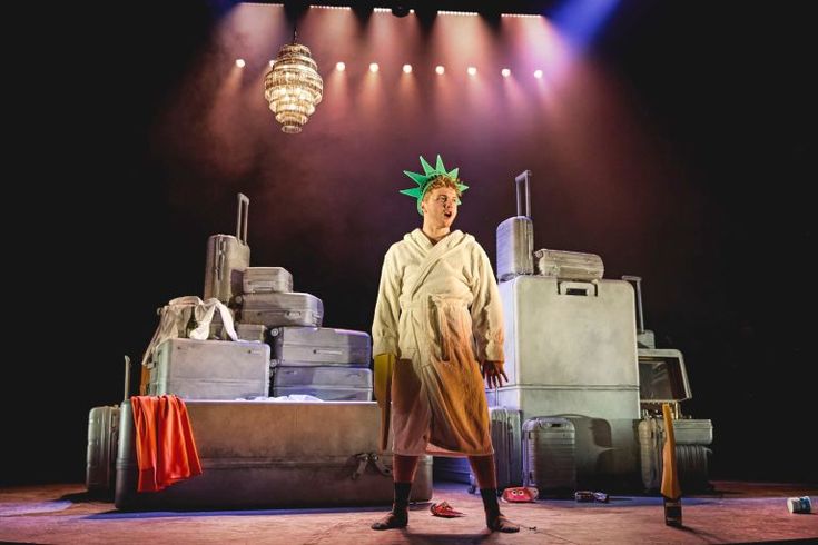 a man standing on top of a stage next to luggage