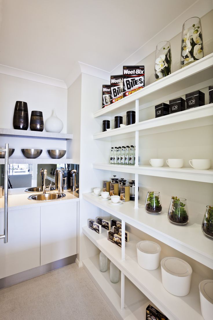 a kitchen with white shelves filled with dishes and cups