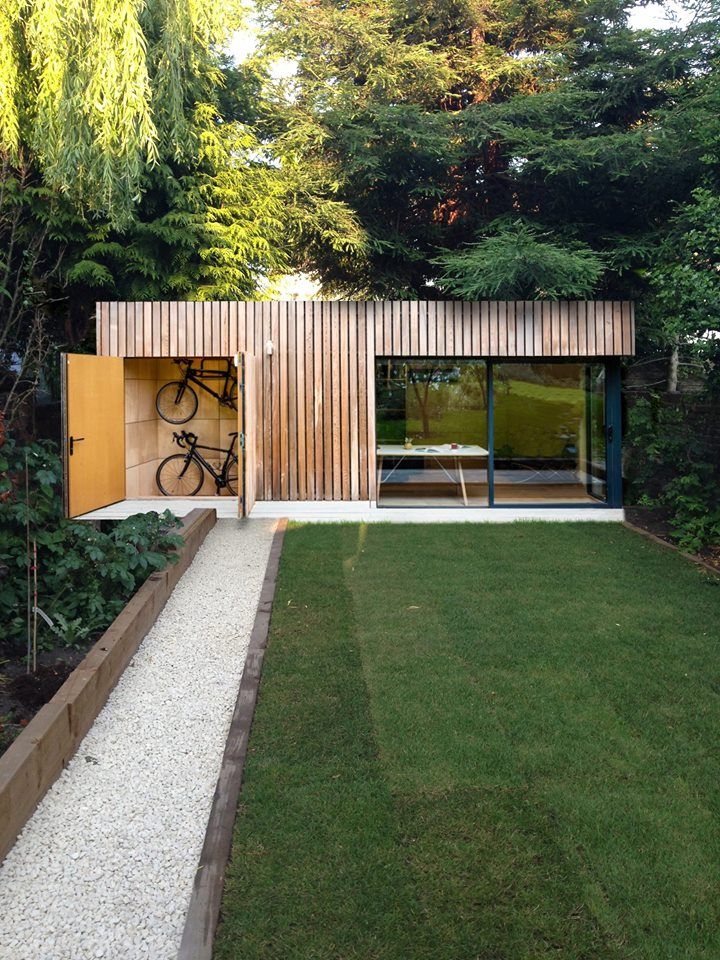 a bike is parked in front of a wooden building with glass doors and windows on the side