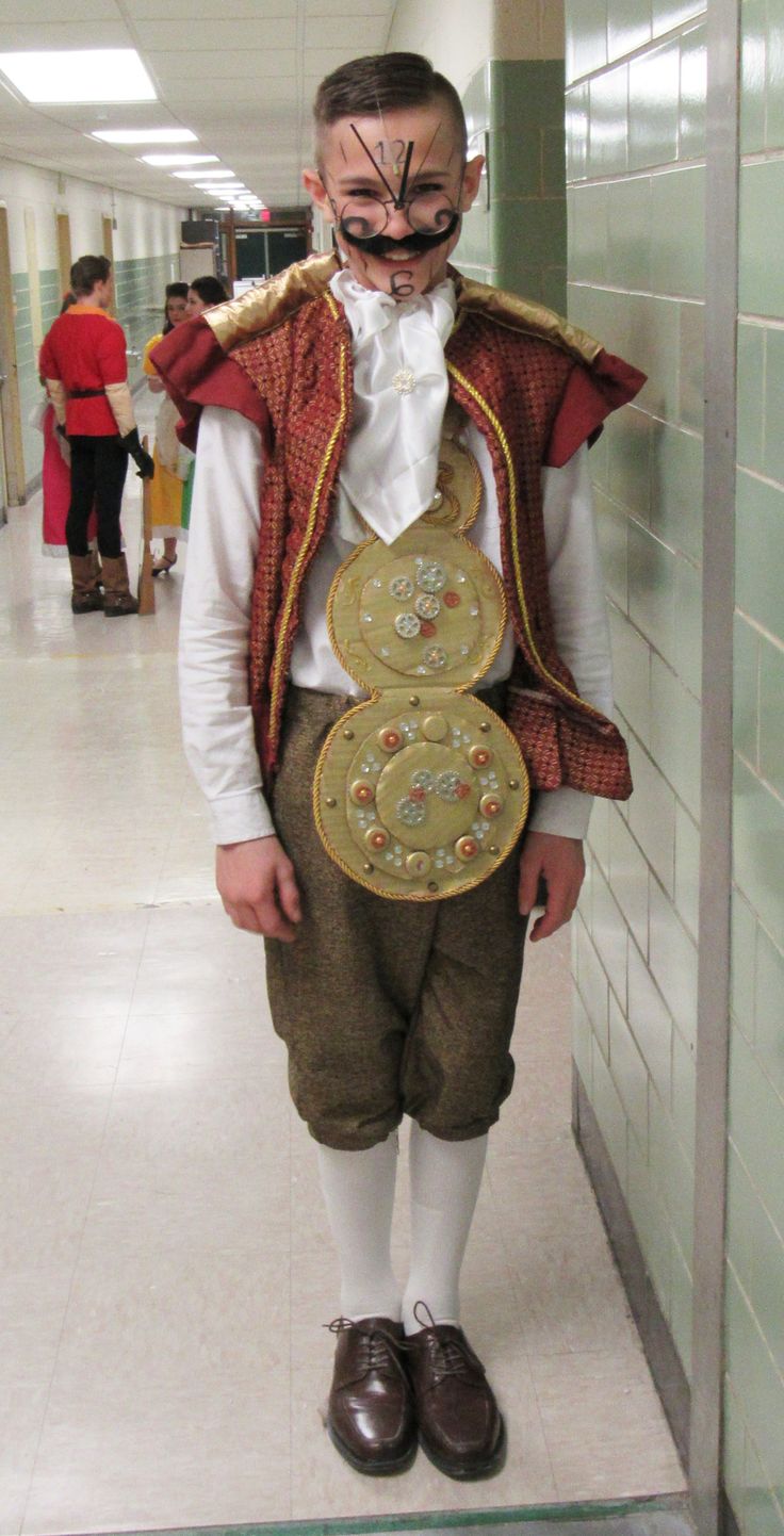 a man in costume standing next to a wall with a clock on it's face