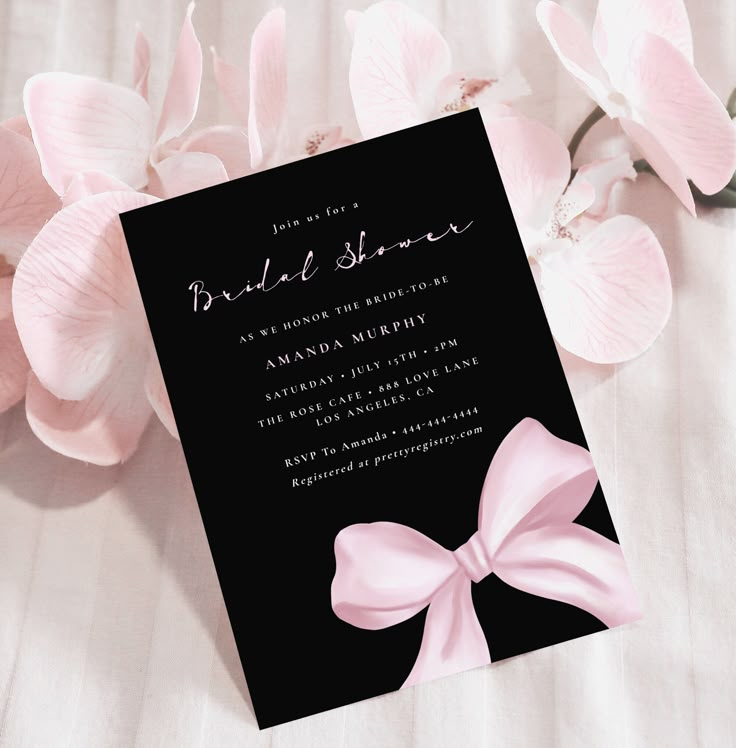 a black and pink bridal shower card with a bow on it next to flowers