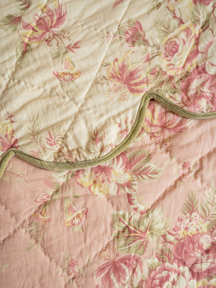 an unmade bed with pink and green floral bedspread on top of it