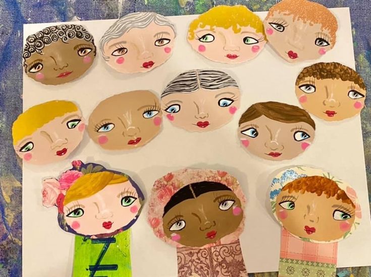 paper doll faces are arranged on top of a piece of paper