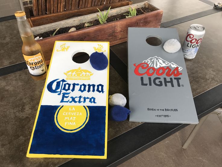 two beer bottles and a cornhole game on a table