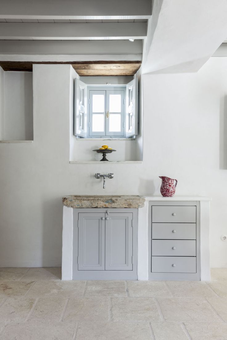 a bathroom with a sink, cabinet and window