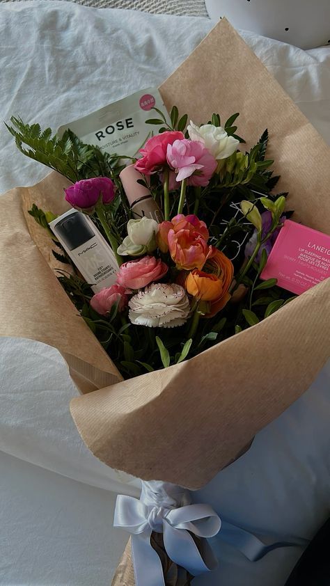 a bouquet of flowers is wrapped in brown paper and tied with a white ribbon on the bed