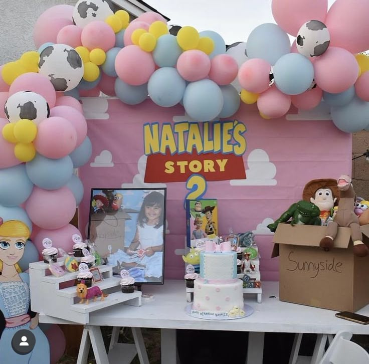 a birthday party with balloons, toys and decorations on the table in front of a pink tent