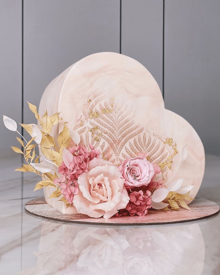 a pink hat with flowers and leaves on it sitting on top of a marble table