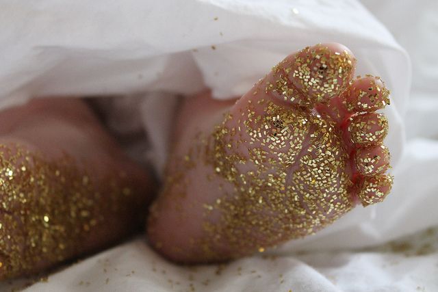 a baby's foot with gold glitter on it and white paper in the background