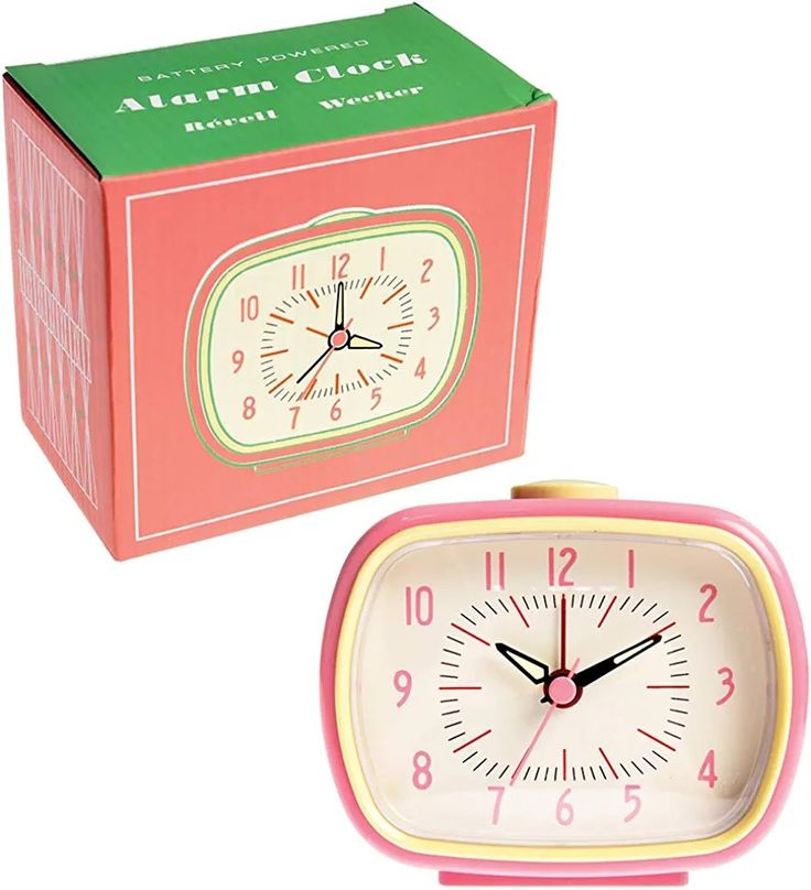 a pink alarm clock sitting next to a green box with numbers on it and the time is 11 55