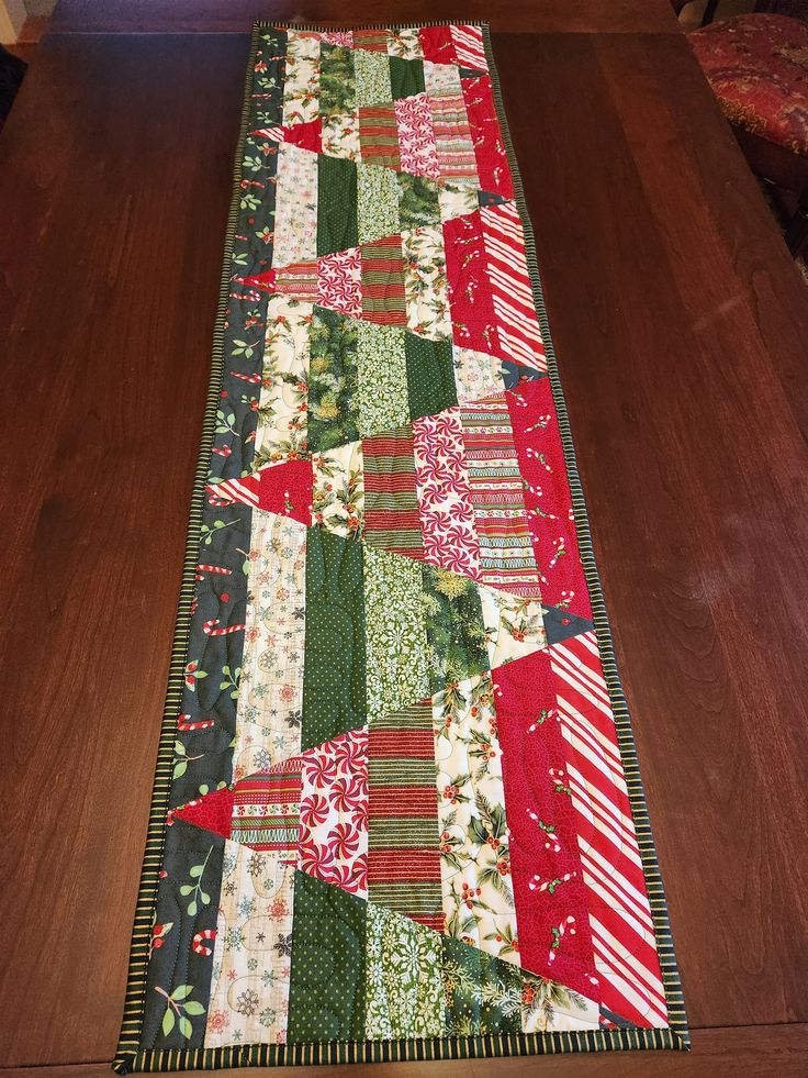 the table runner is made up of many different pieces of quilted fabric, including red and green