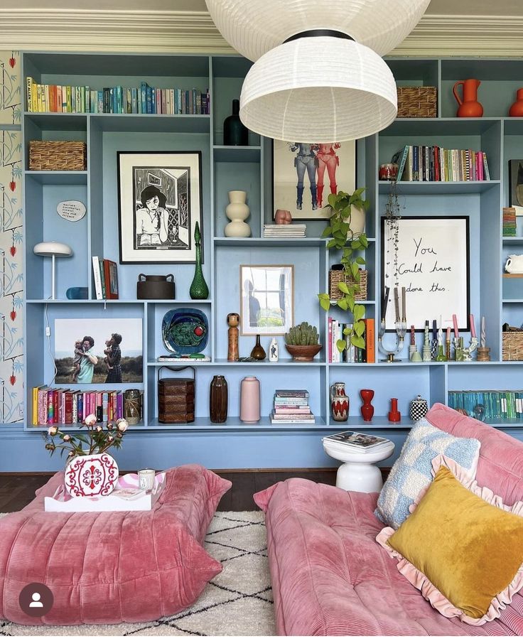 a living room filled with lots of bookshelves covered in pink and blue furniture