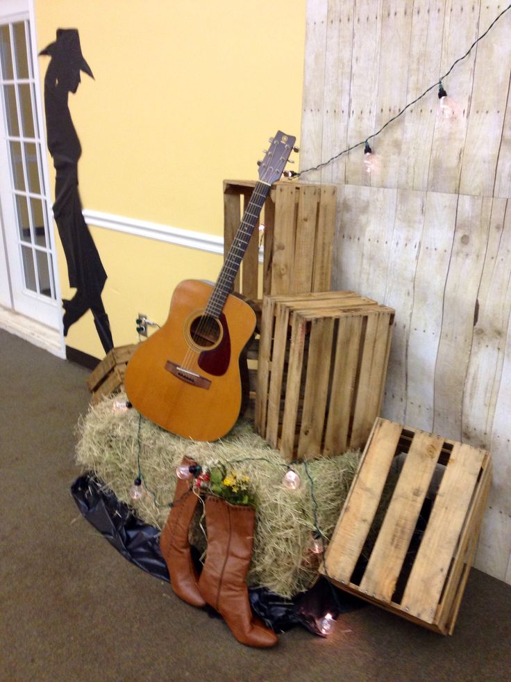 an acoustic guitar sits on hay in front of a wooden crate and some other items