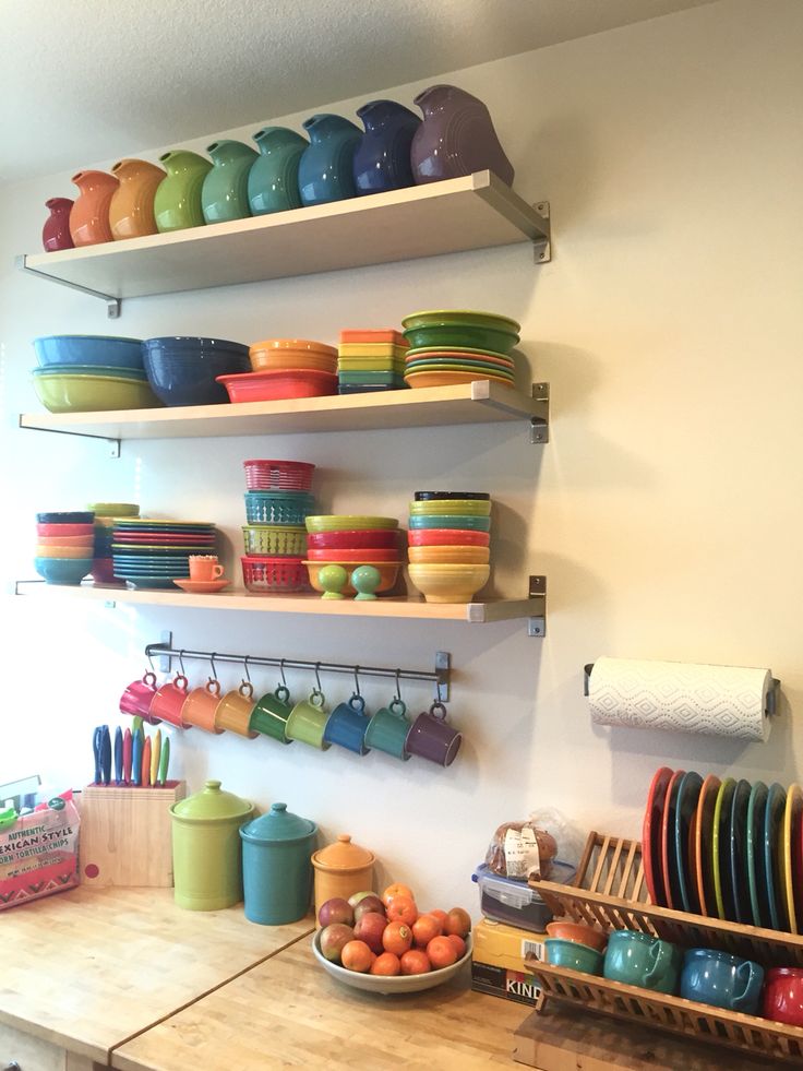 the shelves are full of colorful dishes and bowls on them, along with other kitchen items