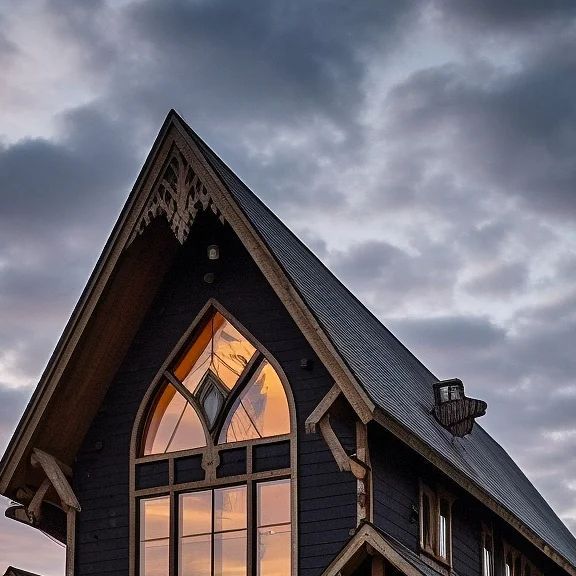 a black house with a large window on the front and side of it at sunset