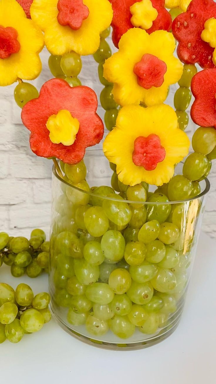 some grapes and flowers are in a vase