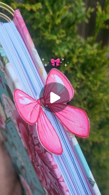 a close up of a person holding an open book with a pink bow on it