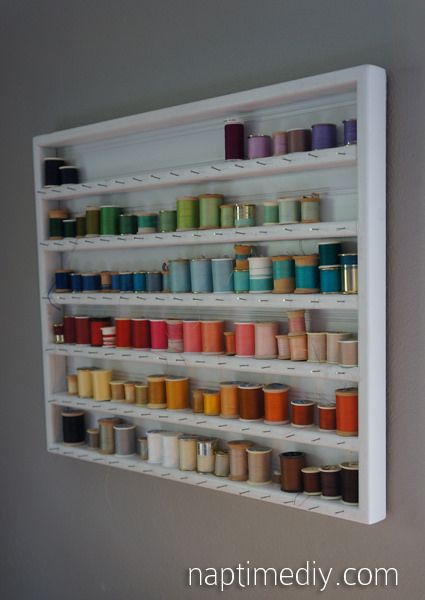 a white shelf filled with lots of spools of thread on top of it