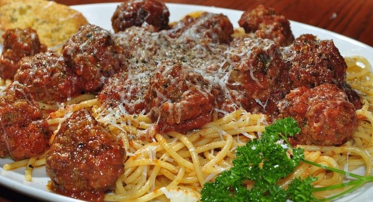 a white plate topped with spaghetti and meatballs covered in grated parmesan cheese