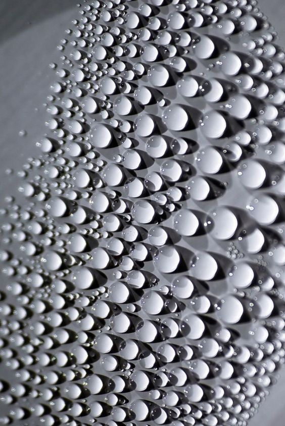 water droplets are arranged in the shape of an abstract pattern on a white surface with black dots