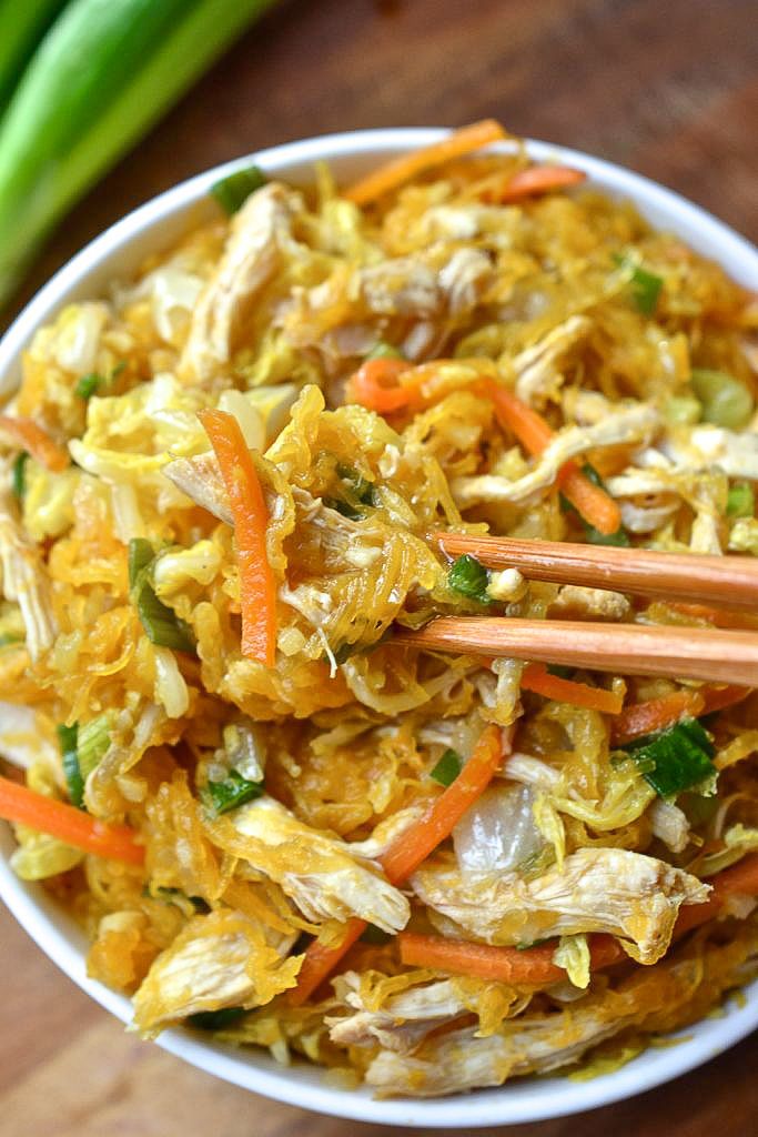 a white bowl filled with food and chopsticks on top of a wooden table