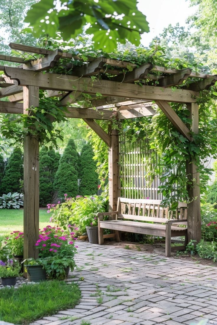 a wooden bench sitting under a pergoline covered arbor in a lush green park