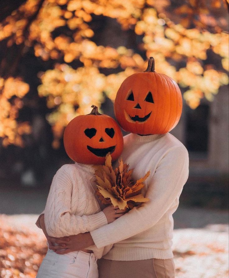 two people hugging each other with pumpkins on their heads