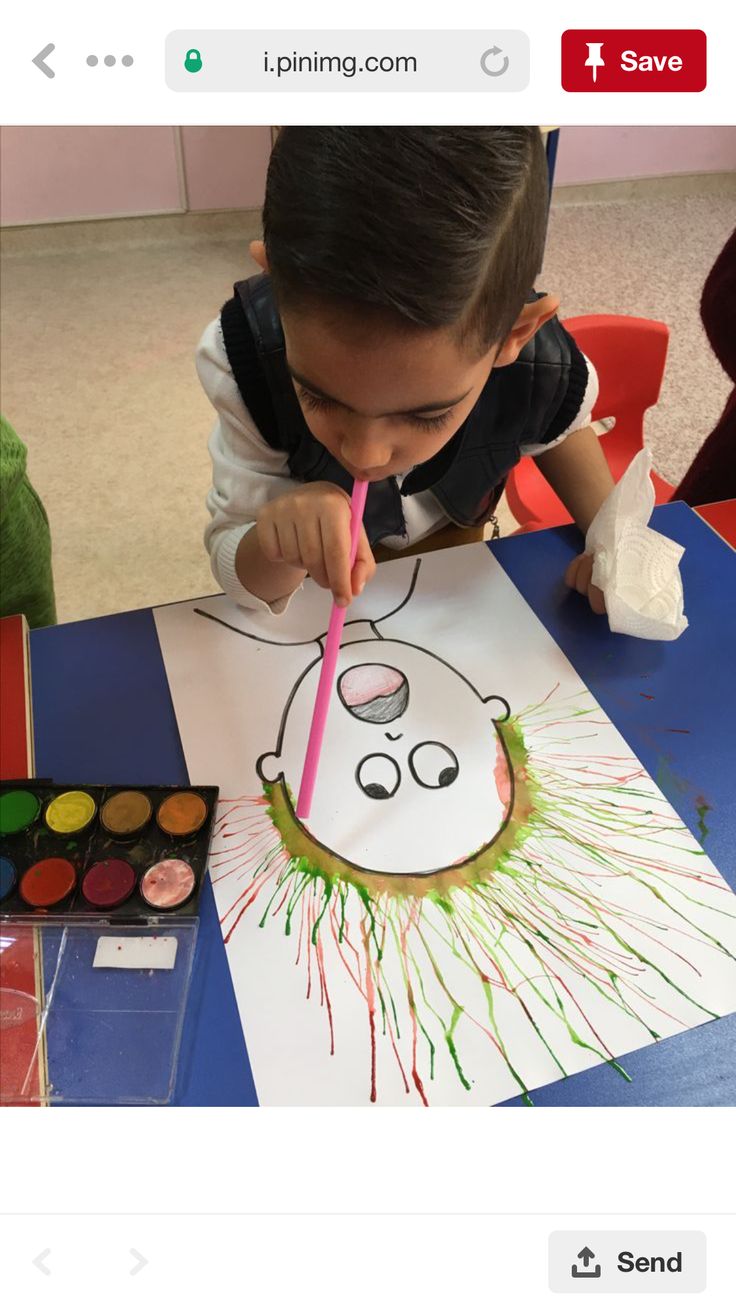 a young boy is painting a face on paper with colored crayons and watercolors