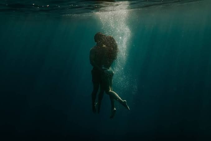 a man and woman are kissing under the water in this underwater photo taken from below