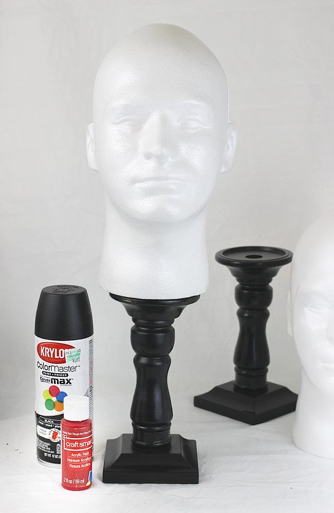 three white mannequin heads with black bases and paint next to each other on a white surface