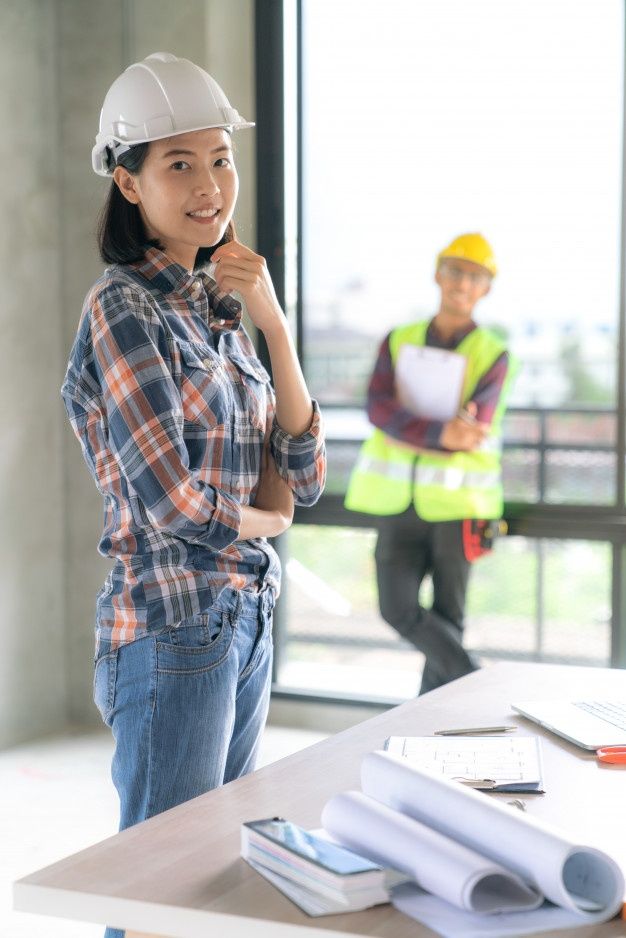 a woman standing in front of a table with construction equipment on it and two men behind her